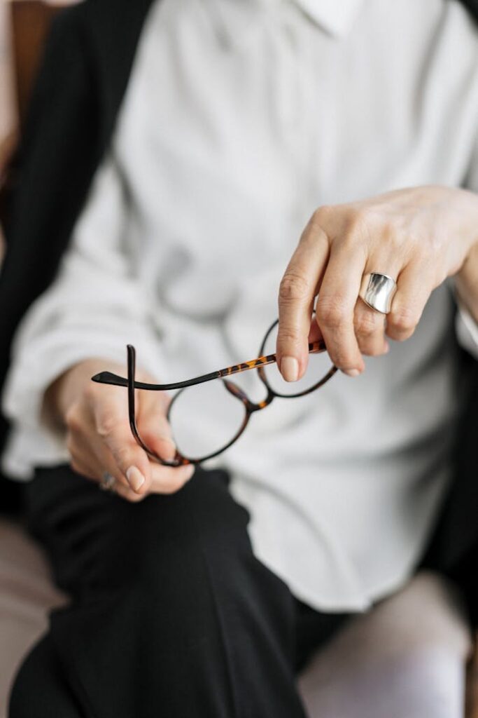 accueil Close-up of a woman holding glasses, symbolizing thought and professionalism.